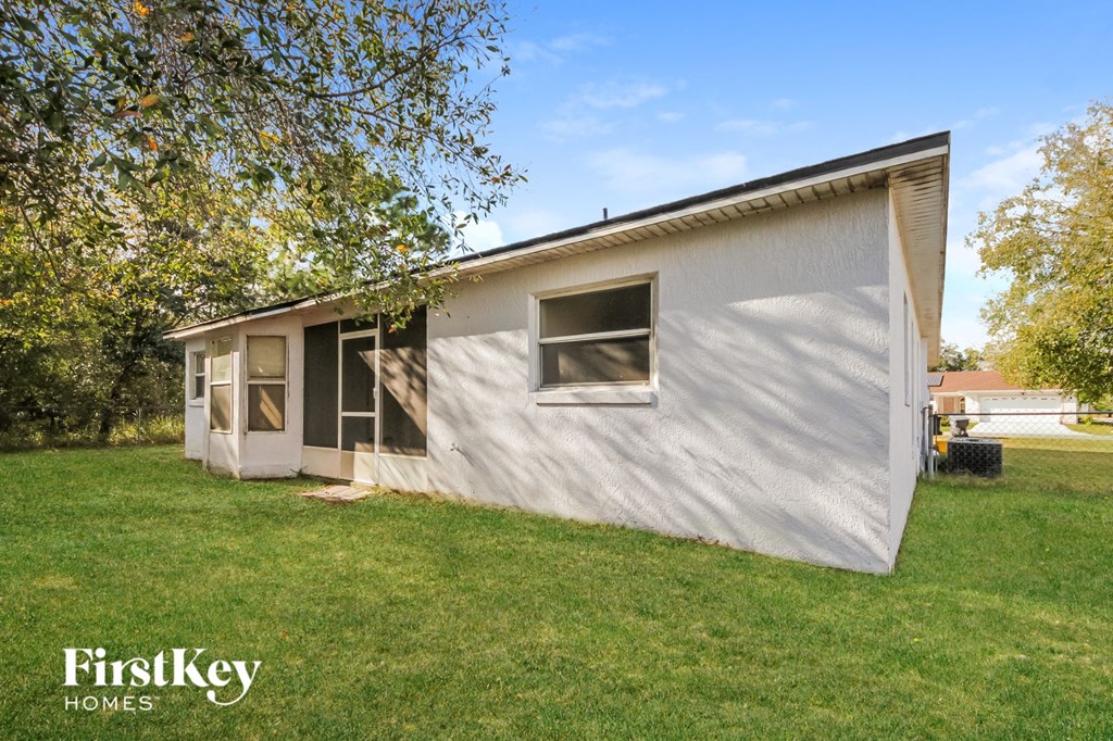 the exterior of a small white house with a lawn and trees