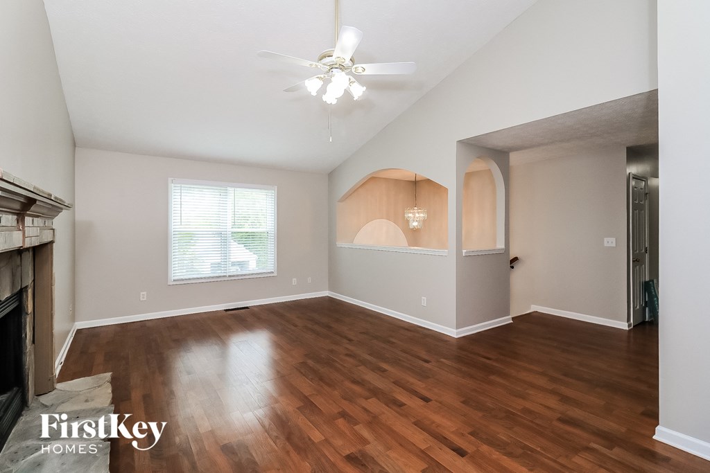 an empty living room with wood floors and a ceiling fan