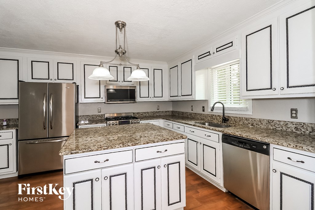a white kitchen with granite counter tops and stainless steel appliances