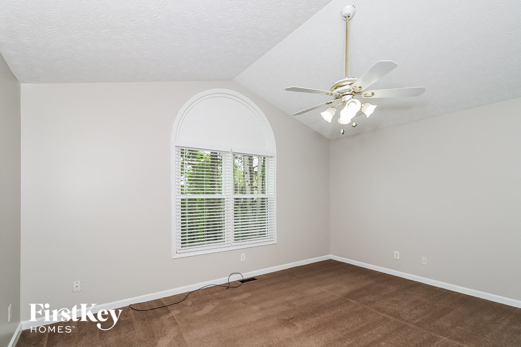 a bedroom with a large window and a ceiling fan