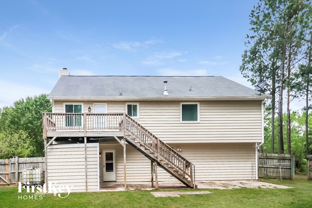 the back of a white house with a porch and a deck
