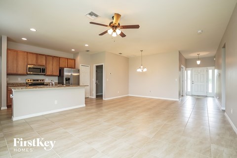 A spacious living room with a ceiling fan and lighting fixtures.