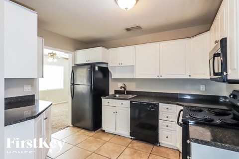 A kitchen with black appliances and white cabinets.