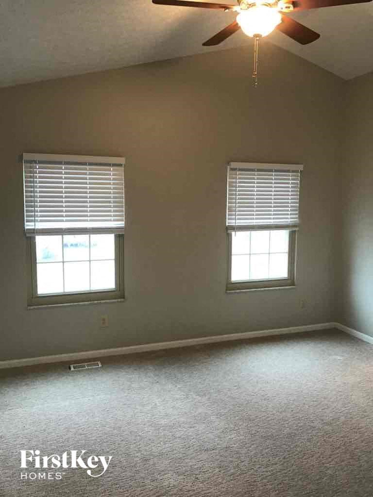 an empty room with two windows and a ceiling fan