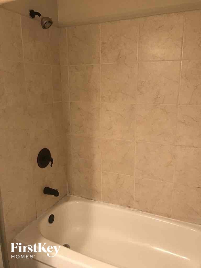 a bath tub in a tiled bathroom with a shower