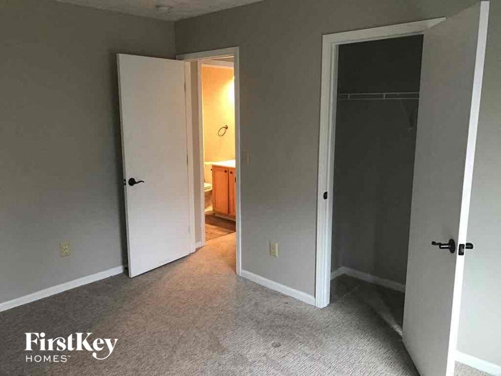 a bedroom with a door open to a bathroom and a closet