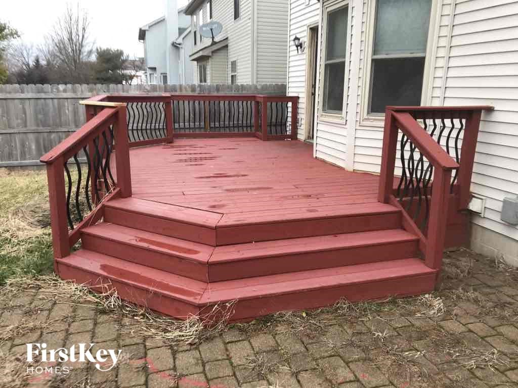 a deck with a wooden railing and stairs in front of a house
