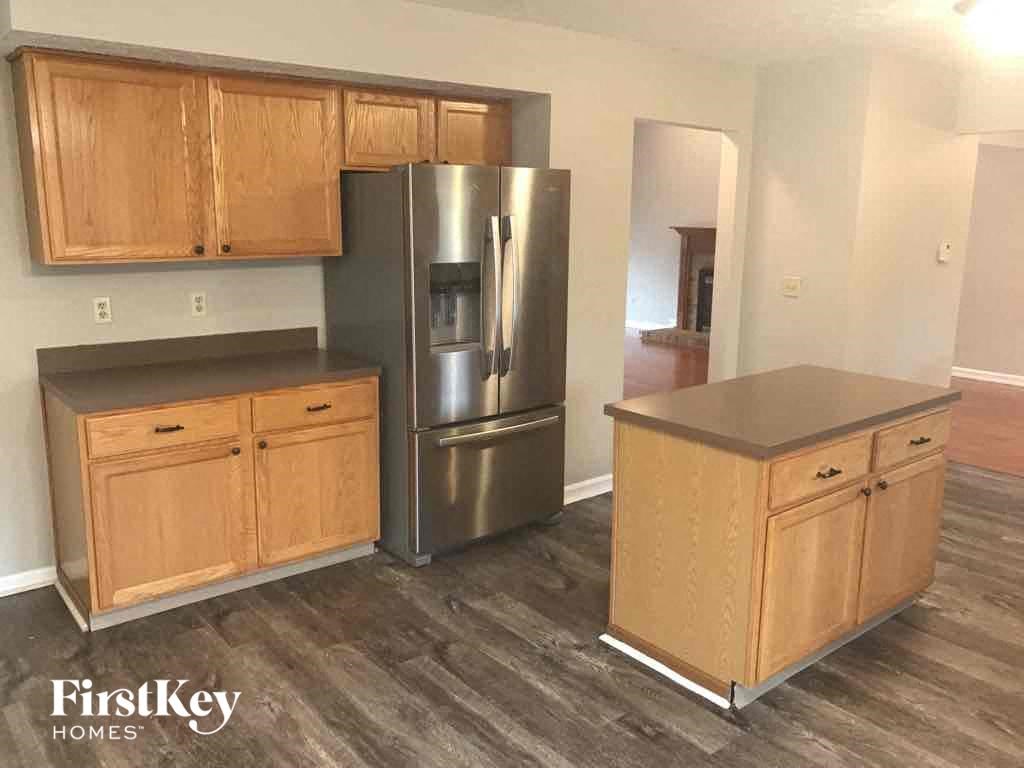 an empty kitchen with wooden cabinets and a stainless steel refrigerator