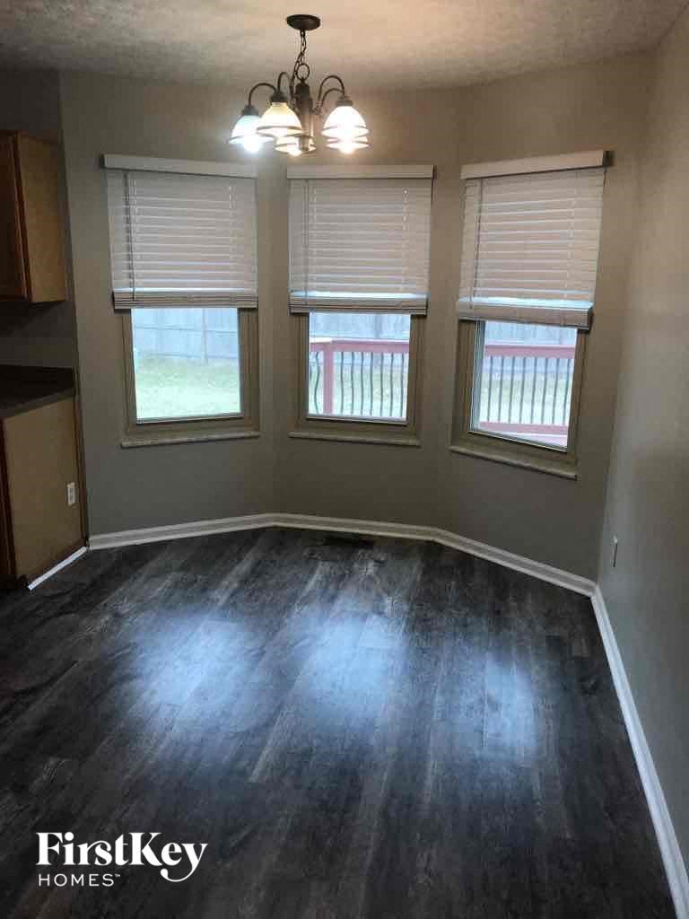 an empty living room with wood floors and three windows