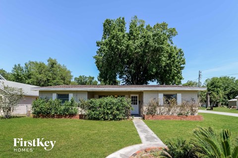 a small white house with a lawn and a tree