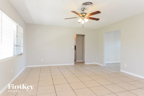 an empty living room with a ceiling fan and tiled floor