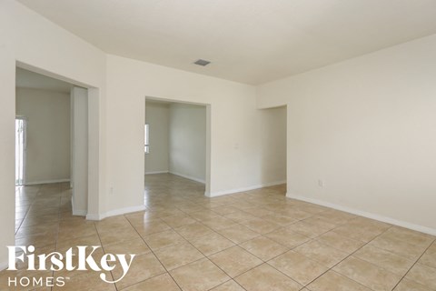 A spacious room with tiled flooring and white walls, part of a property by FirstKey Homes.