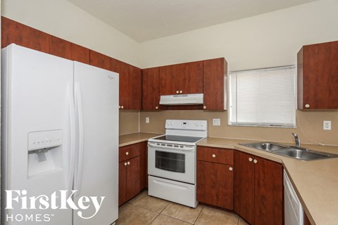 A kitchen with a white fridge, stove and wooden cabinets.