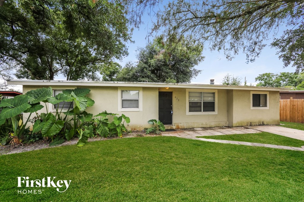a small yellow house with a yard and grass
