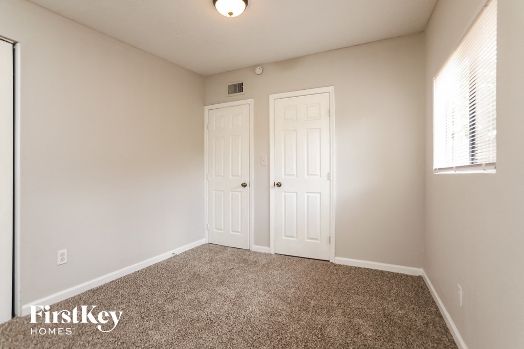 a bedroom with two doors and a carpeted floor and a window