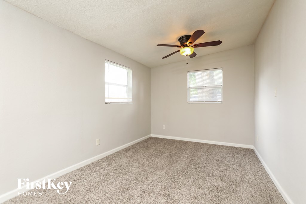 the spacious living room with ceiling fan and carpeting