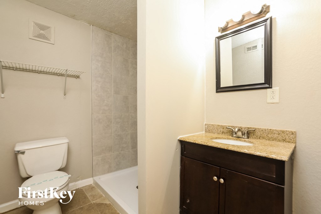 a bathroom with a toilet sink and shower and a mirror