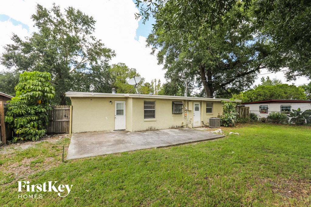 a small yellow house with a yard and a driveway