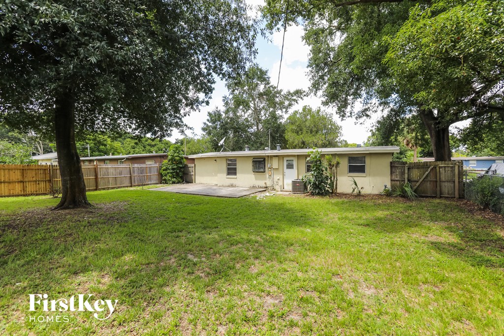 a small yellow house with a yard and trees