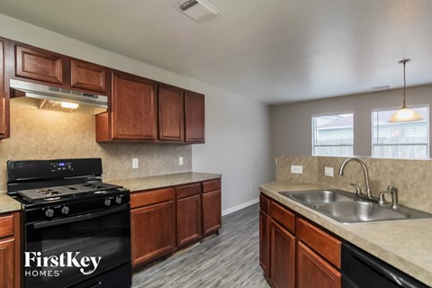 A kitchen with a black stove top oven and wooden cabinets.
