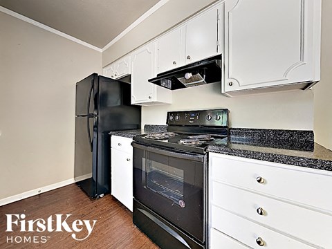 a kitchen with black appliances and white cabinets and a black refrigerator