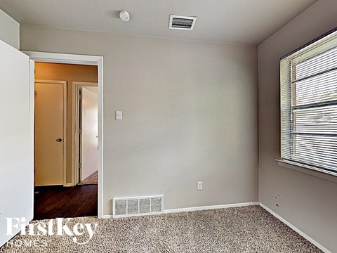 a bedroom with a large window and a door to a hallway