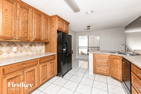 A kitchen with wooden cabinets and a black refrigerator.