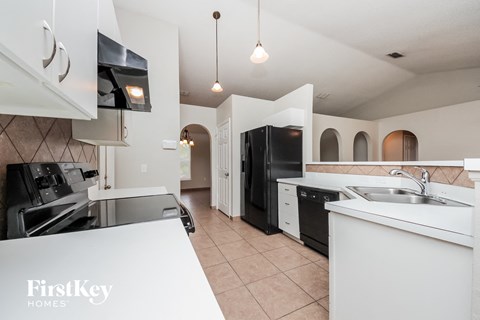 a white kitchen with black appliances and white counters