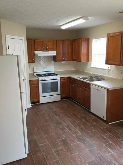 A kitchen with brown cabinets and a white fridge.