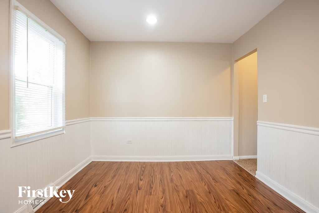 a living room with wood floors and white walls and a window