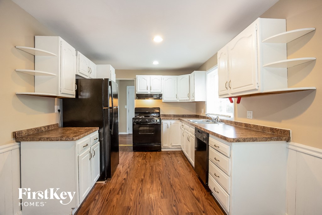 a kitchen with white cabinets and black appliances and wood floors