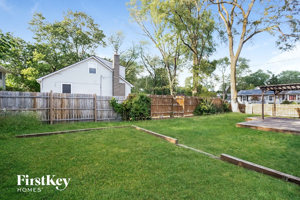 a backyard with a fence and a white house