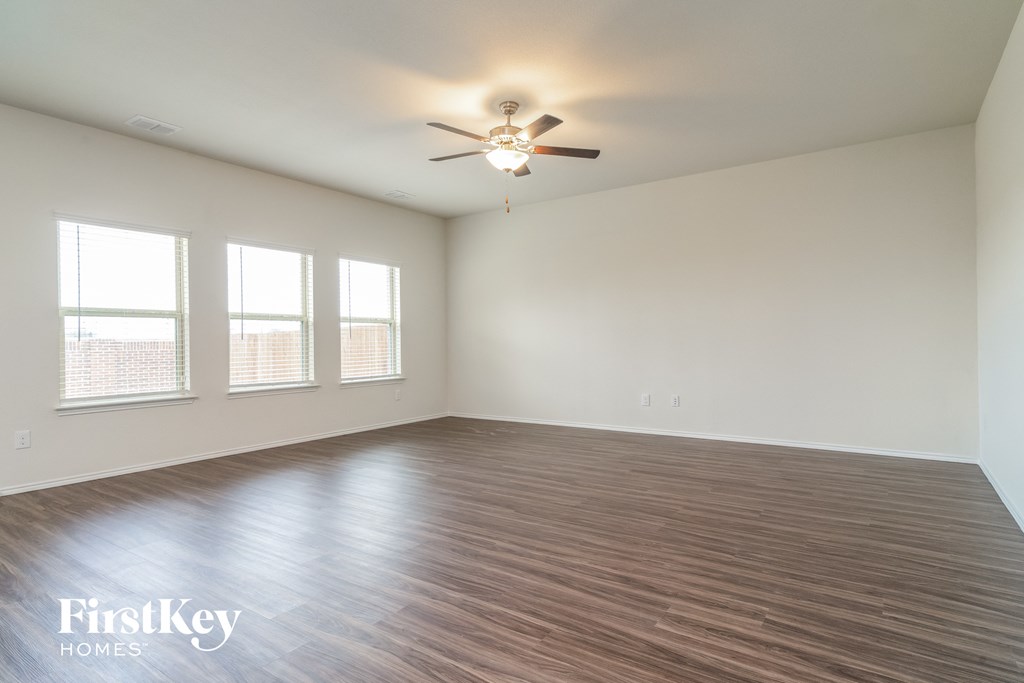 an empty living room with wood floors and a ceiling fan