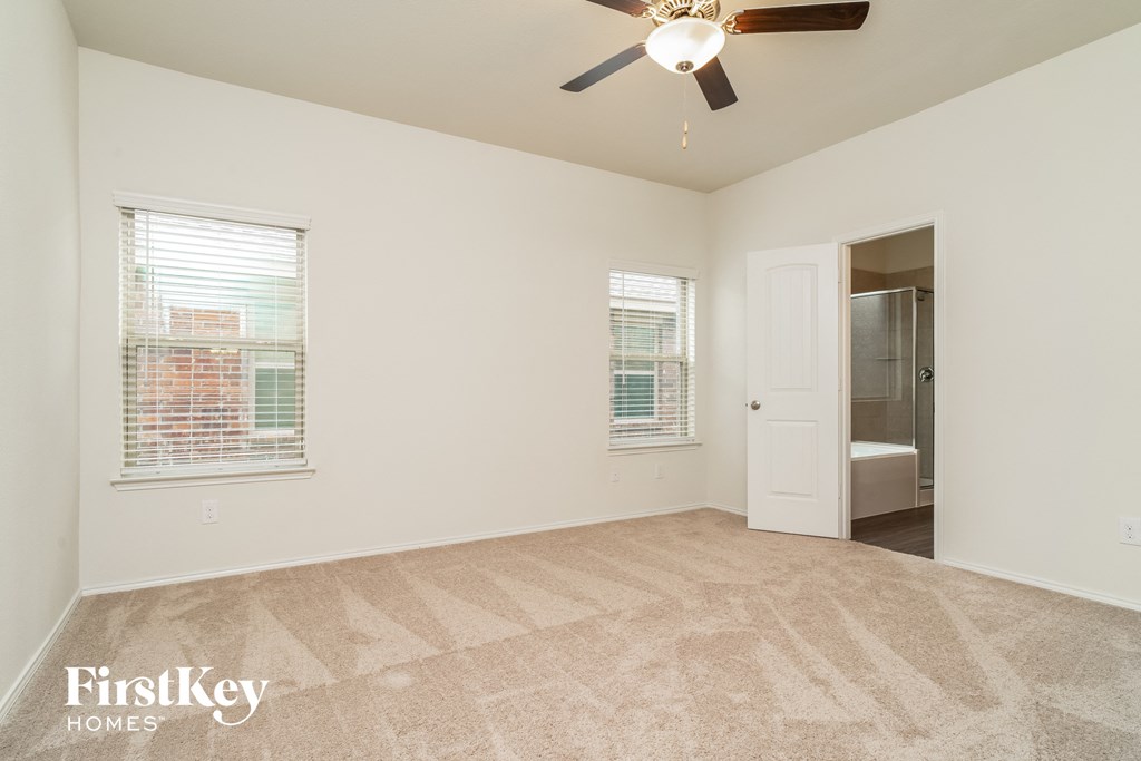 a living room with a ceiling fan and a door to a bathroom