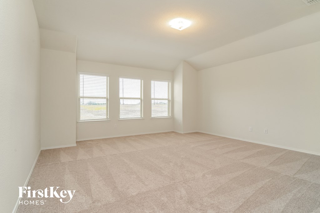 a spacious living room with three windows and a carpeted floor