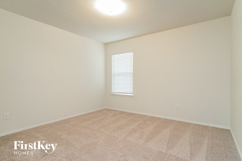 the spacious living room of an apartment with beige carpet and a window