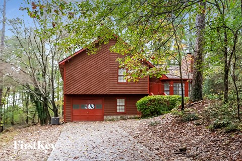 A red house with a garage number 43 is surrounded by trees.