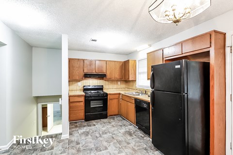 A kitchen with a black fridge and wooden cabinets.