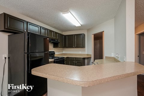 A kitchen with a black refrigerator and brown cabinets.