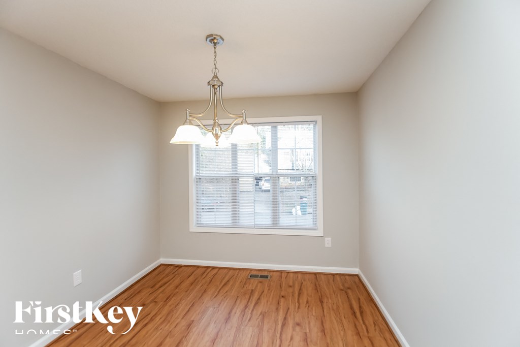 an empty dining room with wood floors and a chandelier