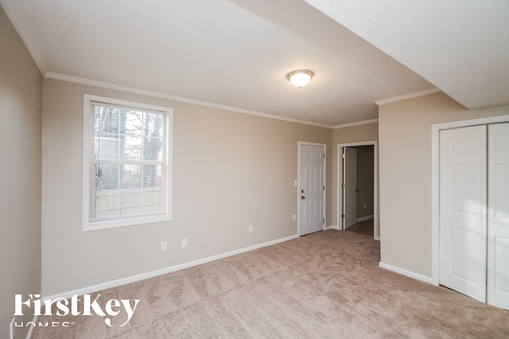 a bedroom with a carpeted floor and a door to a closet
