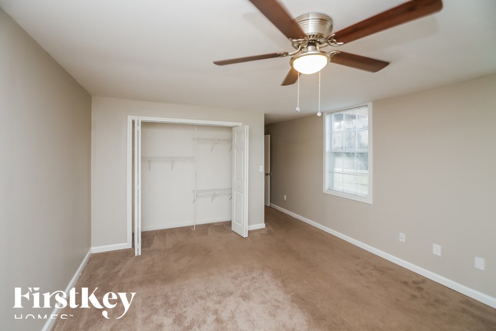 an empty living room with a ceiling fan and a closet