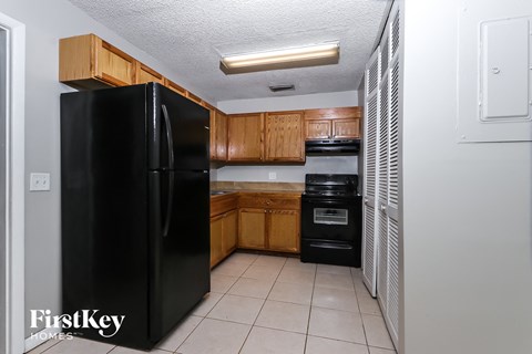 A black refrigerator is in a kitchen with wooden cabinets.