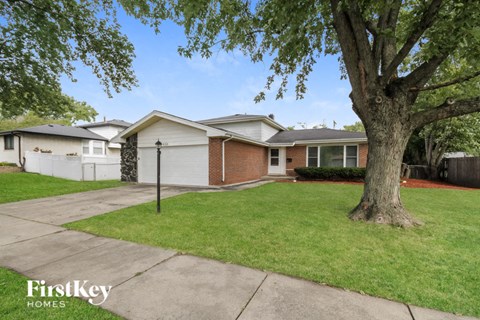 a white and brick house with a yard and a tree