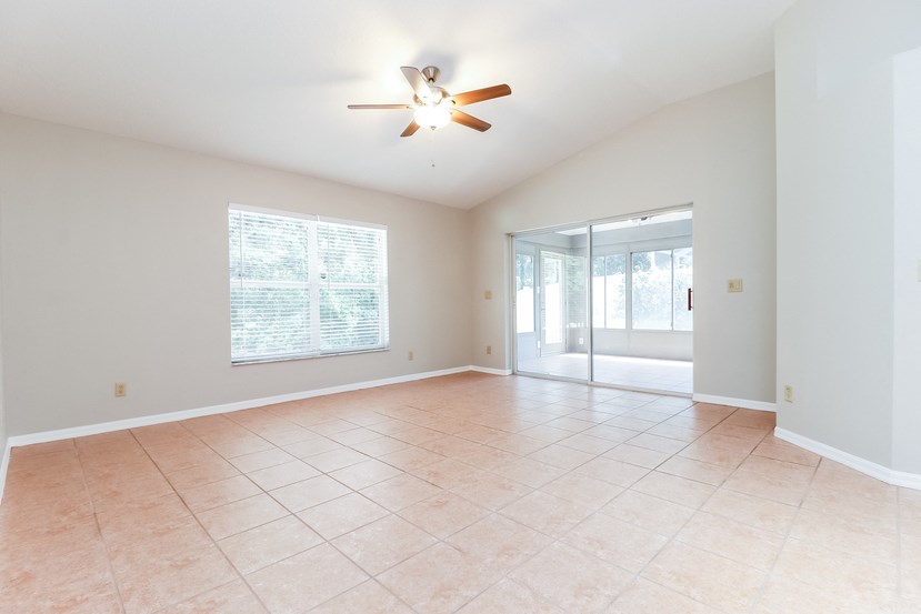 an empty living room with a ceiling fan and a tiled floor