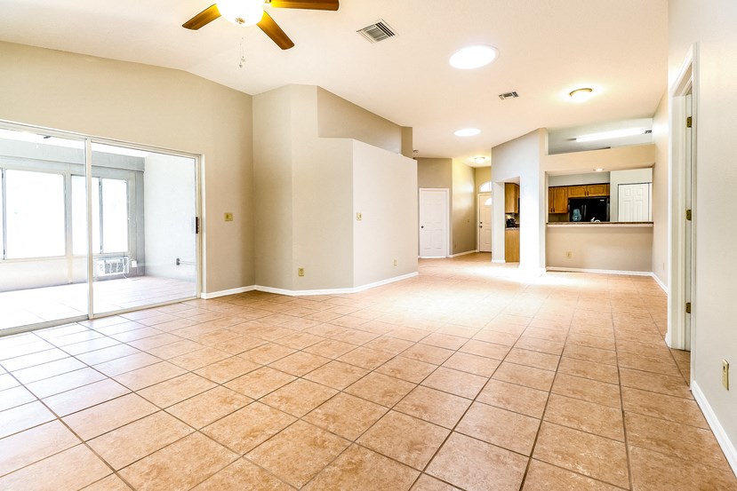 an empty living room with a ceiling fan and tile flooring