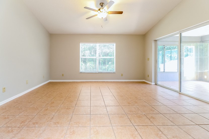 an empty living room with a ceiling fan and a sliding glass door