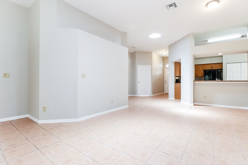 an empty living room and kitchen with white walls and tiled floors