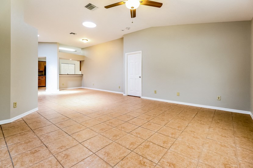 an empty living room with a ceiling fan