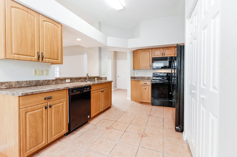 a large kitchen with wooden cabinets and black appliances